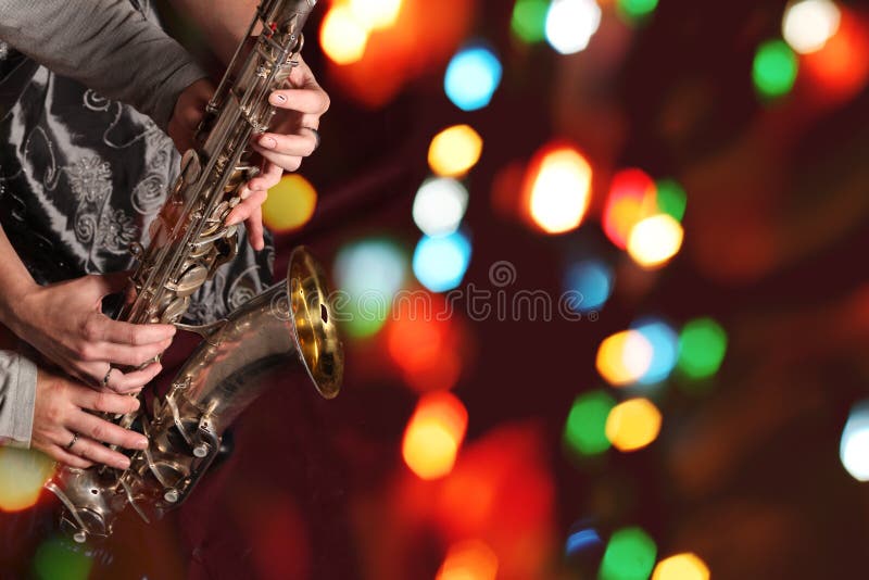 Le mani della donna e dell'uomo con il sassofono sulle luci del bokeh fotografia stock libera da diritti Le mani della donna e dell'uomo con il sassofono sulle luci del bokeh fotografia stock libera da diritti
