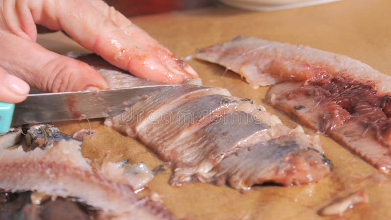 Le mani delle donne tagliano le aringhe al rallentatore della cucina domestica