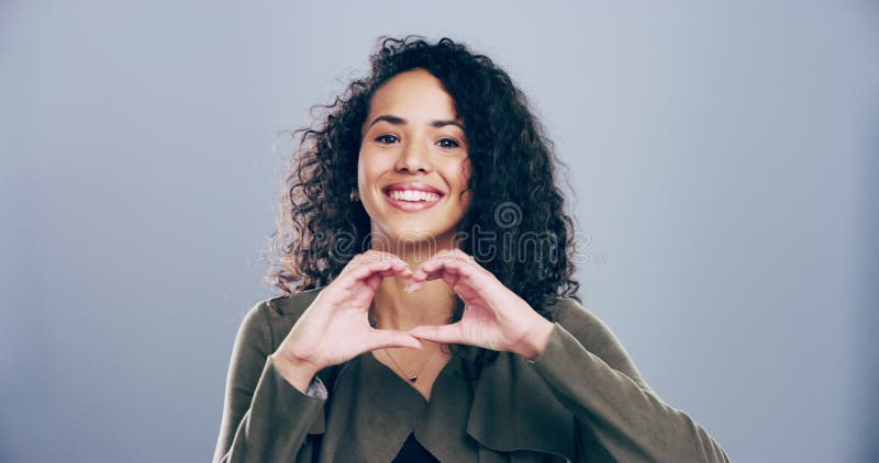 Le mani di cuore sorridono e le donne in studio ritraggono per cura carità e pace con positività alla gentilezza. giovane