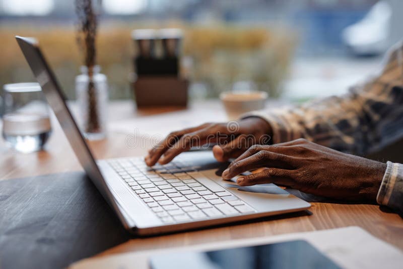 Le mani di giovani soldatari che digitano sulla tastiera del portatile per tavolo al bar immagini stock