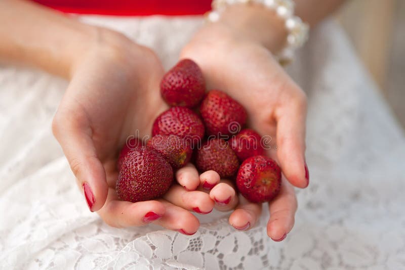 Le mani femminili tengono una manciata di fragole immagine stock libera da diritti Le mani femminili tengono una manciata di fragole immagine stock libera da diritti