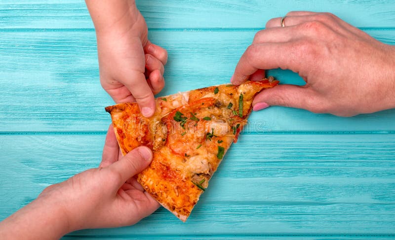 Le mani vogliono prendere l'ultimo pezzo di pizza dalla tavola fotografie stock Le mani vogliono prendere l'ultimo pezzo di pizza dalla tavola fotografie stock