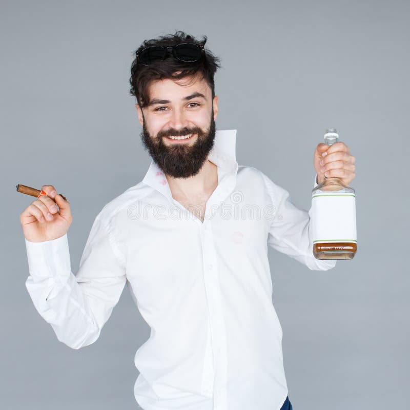 Le mannen med skägget som rymmer en flaska av whisky arkivbild Le mannen med skägget som rymmer en flaska av whisky arkivbild