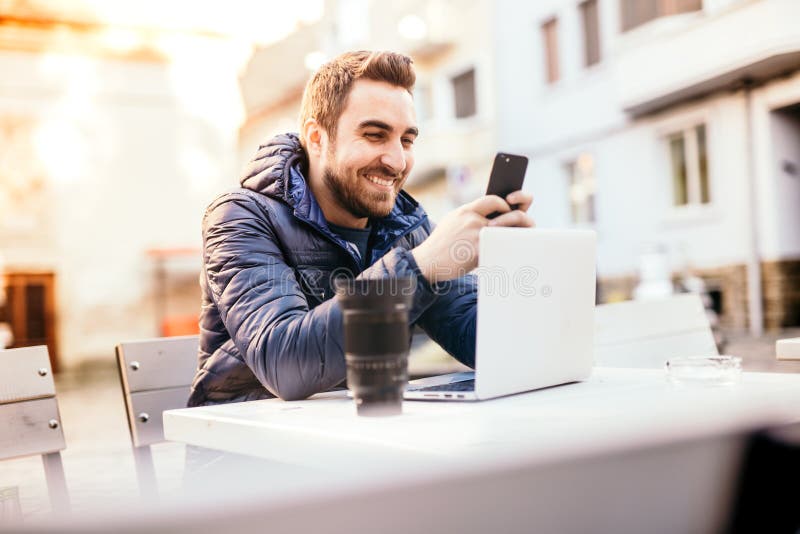 Le mannen som arbetar från utomhus- kontor och överföring av meddelanden på smartphonen i stads- miljö royaltyfri bild Le mannen som arbetar från utomhus- kontor och överföring av meddelanden på smartphonen i stads- miljö royaltyfri bild