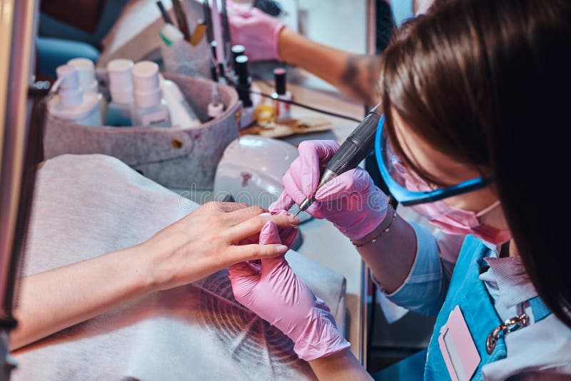 Le manucure diligent focalis? travaille sur son lieu de travail au salon de manucure images libres de droits Le manucure diligent focalis? travaille sur son lieu de travail au salon de manucure images libres de droits