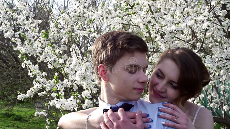 Le marié de jeune mariée embrasse doucement le jardin de cou au printemps