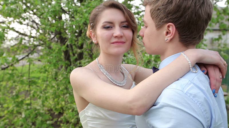 Le marié de jeune mariée embrasse doucement le jardin de cou au printemps