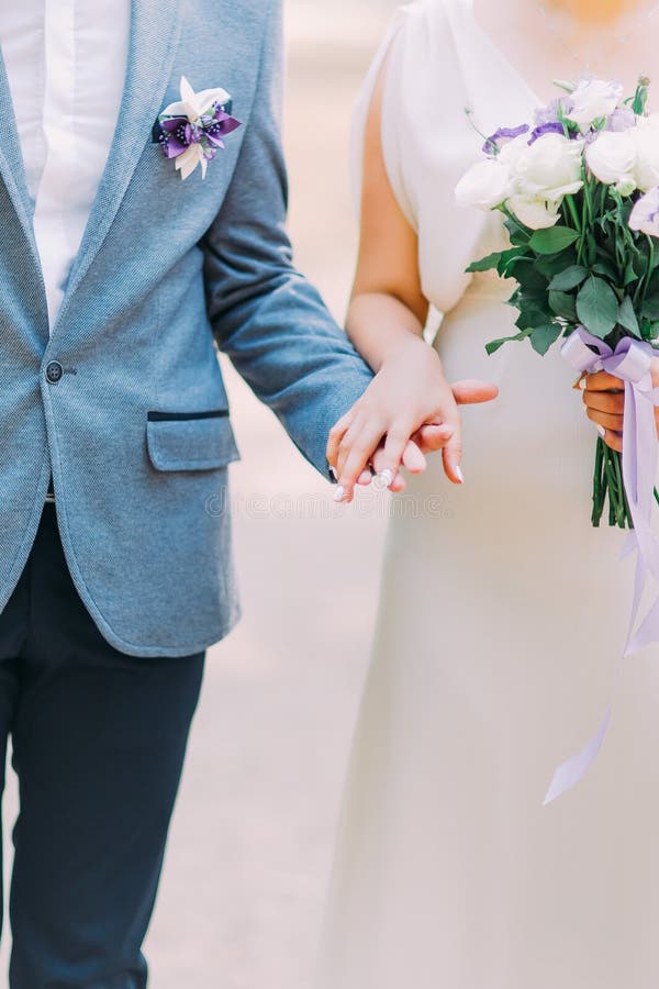 Le marié habillé élégant tenant la main de sa belle jeune mariée, épousant des couples marche sur le fond de jardin photos libres de droits Le marié habillé élégant tenant la main de sa belle jeune mariée, épousant des couples marche sur le fond de jardin photos libres de droits