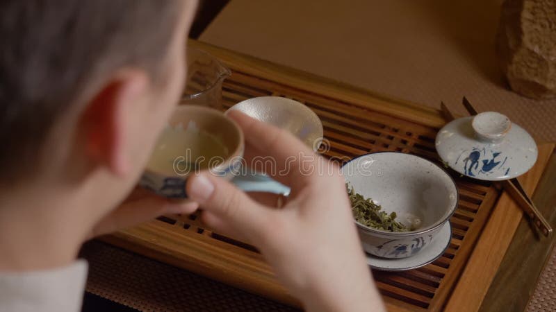 Le maître de thé verse l'infusion de la tasse d'équité dans la cuvette et boit du thé chinois banque de vidéos