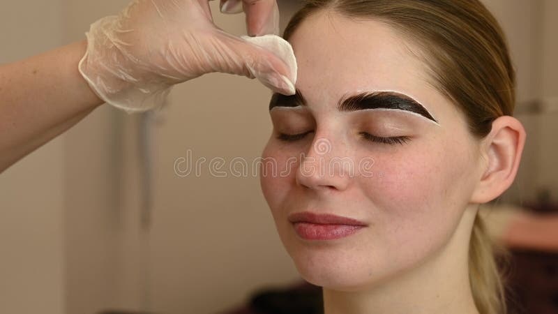 Le maître peint les sourcils d'une femme.