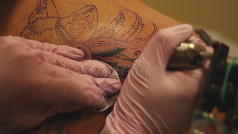 Le maître peint un tatouage avec un dessin de la mort sur l'épaule d'un homme