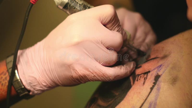 Le maître peint un tatouage avec un dessin de la mort sur l'épaule d'un homme
