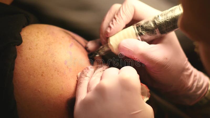 Le maître peint un tatouage avec un dessin de la mort sur l'épaule d'un homme