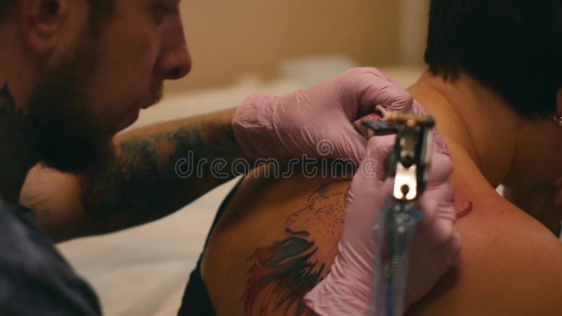 Le maître peint un tatouage avec un dessin de la mort sur l'épaule d'un homme