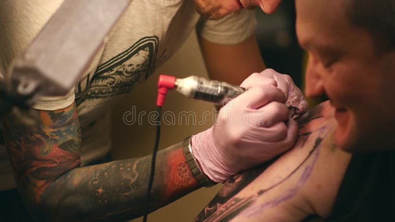 Le maître peint un tatouage avec un dessin de la mort sur l'épaule d'un homme