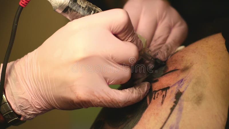 Le maître peint un tatouage avec un dessin de la mort sur l'épaule d'un homme