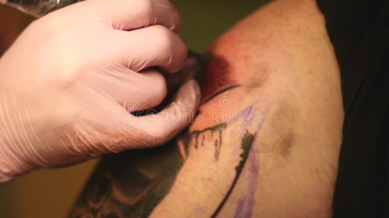 Le maître peint un tatouage avec un dessin de la mort sur l'épaule d'un homme