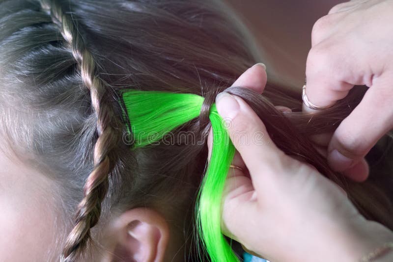 Le maître tisse un brin coloré dans le girl& x27 ; tresse de s image stock Le maître tisse un brin coloré dans le girl& x27 ; tresse de s image stock