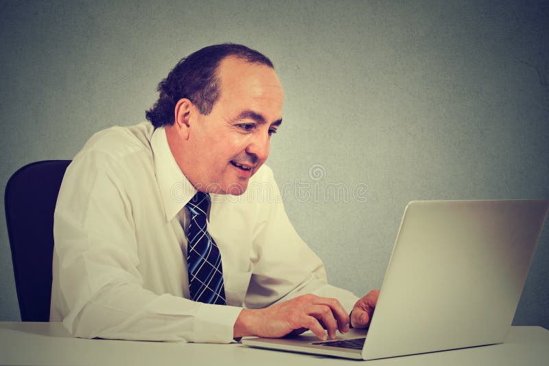 Le milieu heureux a vieilli l'homme d'affaires travaillant avec l'ordinateur portable dans le bureau images stock Le milieu heureux a vieilli l'homme d'affaires travaillant avec l'ordinateur portable dans le bureau images stock