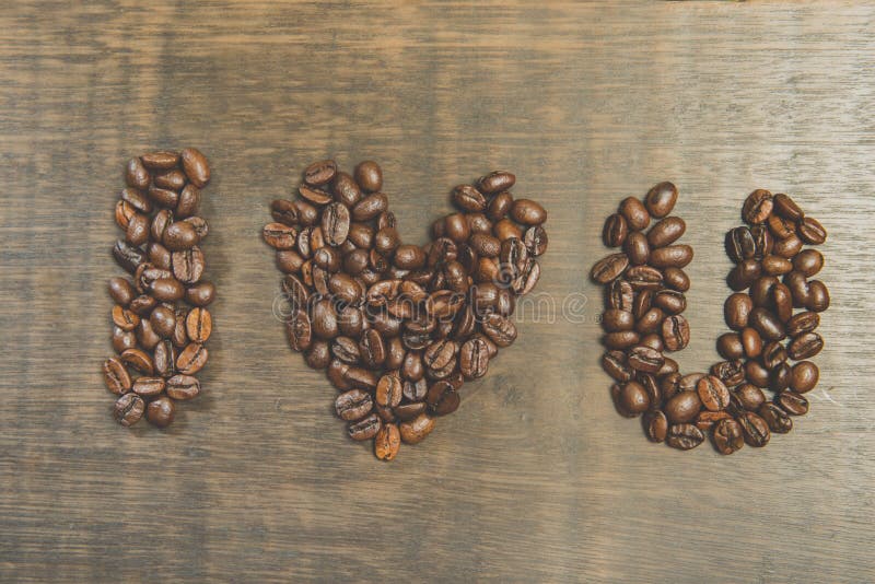 Le mot je t'aime fait à partir des grains de café sur la table en bois Stil photo stock Le mot je t'aime fait à partir des grains de café sur la table en bois Stil photo stock