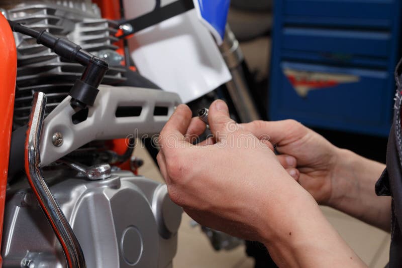 Le motocycliste remplace, des contrôles que la lueur branchent une moto photographie stock Le motocycliste remplace, des contrôles que la lueur branchent une moto photographie stock