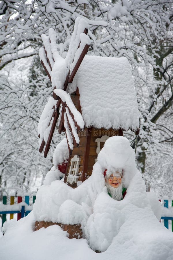 Le moulin à vent décoratif et le gnome couverts de neige fraîche en hiver se garent photo libre de droits Le moulin à vent décoratif et le gnome couverts de neige fraîche en hiver se garent photo libre de droits