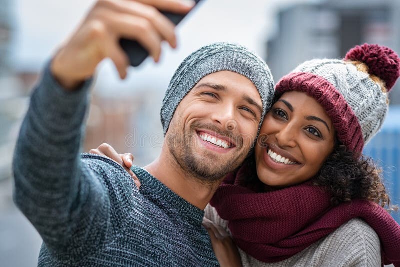 Le multietniska par som tar selfie i vinter royaltyfria bilder Le multietniska par som tar selfie i vinter royaltyfria bilder