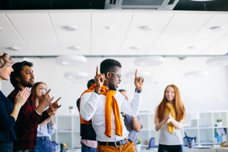 Le mâle africain danse avec les doigts augmentés tandis que ses amis battent des mains photographie stock Le mâle africain danse avec les doigts augmentés tandis que ses amis battent des mains photographie stock