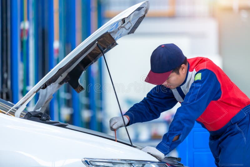 Le mécanicien de voiture de jeune homme à un centre de service des réparations de voiture analyse des problèmes de moteur et véri photos libres de droits Le mécanicien de voiture de jeune homme à un centre de service des réparations de voiture analyse des problèmes de moteur et véri photos libres de droits