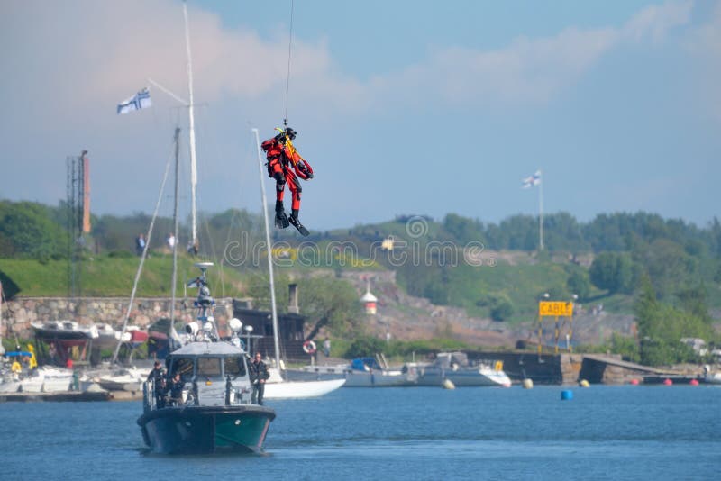 Le nageur finlandais non identifié de délivrance de la garde côtière se laisse tomber vers le bas à la mer baltique image libre de droits Le nageur finlandais non identifié de délivrance de la garde côtière se laisse tomber vers le bas à la mer baltique image libre de droits