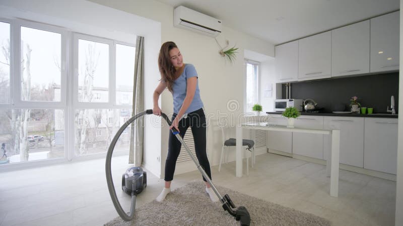 Le nettoyage de maison d'amusement, femme attirante de femme au foyer faisant des vides de nettoyage et la danse gaie et chante d