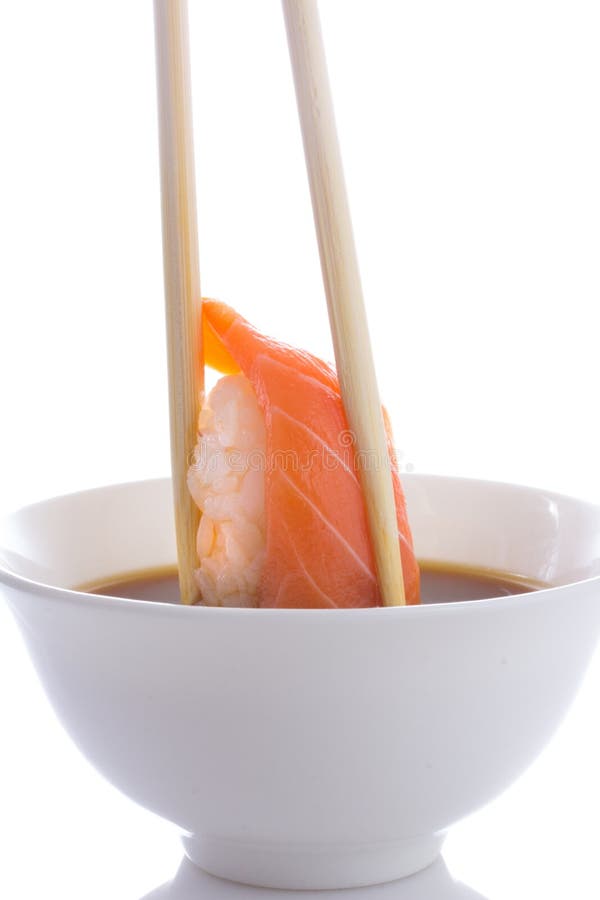 Le nigiri de sushi en baguettes a plongé en sauce de soja d'isolement photos libres de droits Le nigiri de sushi en baguettes a plongé en sauce de soja d'isolement photos libres de droits