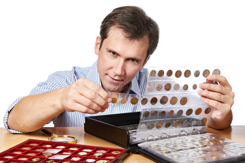 Le numismate d'homme examine sa collection de pièce de monnaie