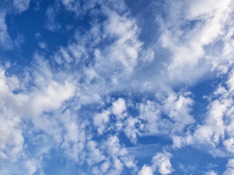 Le nuvole bianche e gonfie in cielo blu con il getto ed il raggiro trascinano