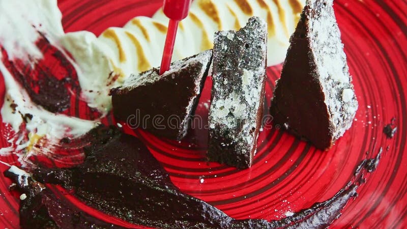 Le panorama de gros plan sur le gâteau en tranches décoré à la mode de brownies a servi de la plaque rouge banque de vidéos