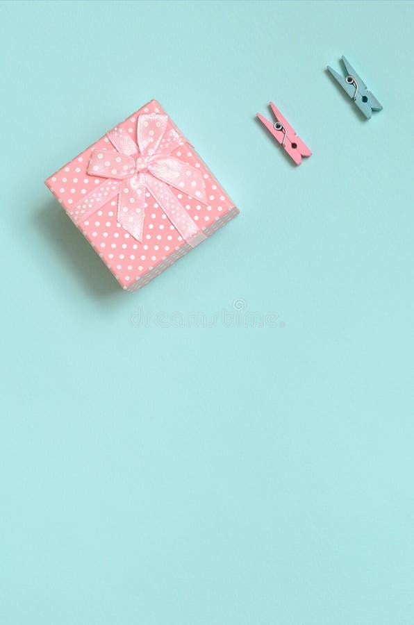 Le petit boîte-cadeau rose et deux chevilles se trouvent sur le fond de texture du papier bleu en pastel de couleur de mode dans images libres de droits Le petit boîte-cadeau rose et deux chevilles se trouvent sur le fond de texture du papier bleu en pastel de couleur de mode dans images libres de droits