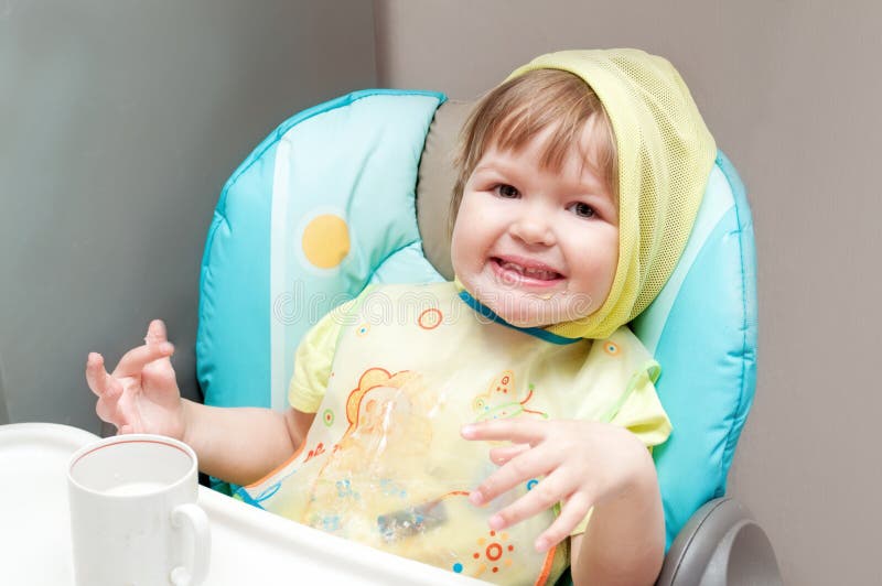Le petit bébé d'un an mange au highchair image libre de droits Le petit bébé d'un an mange au highchair image libre de droits