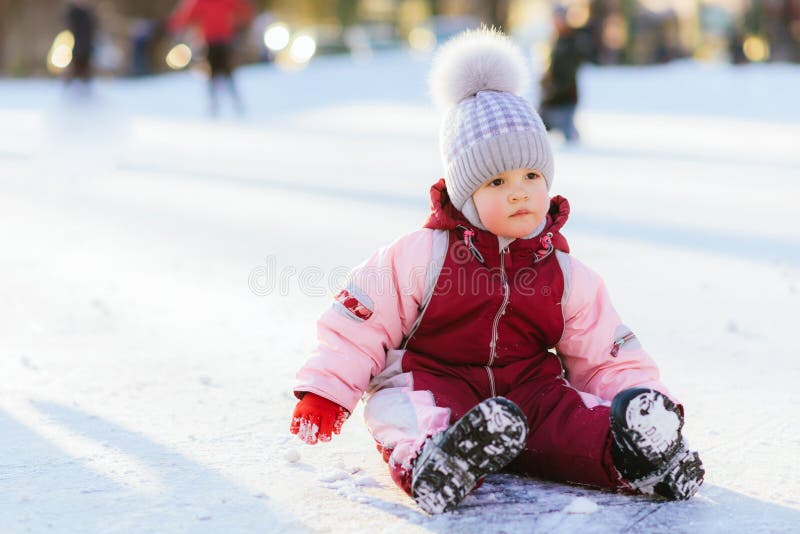 Le petit bébé s'assied sur la neige au coucher du soleil image stock Le petit bébé s'assied sur la neige au coucher du soleil image stock