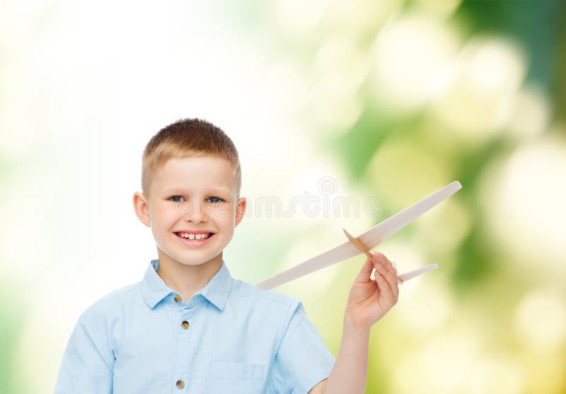 Le petit garçon de sourire tenant un avion en bois modèlent