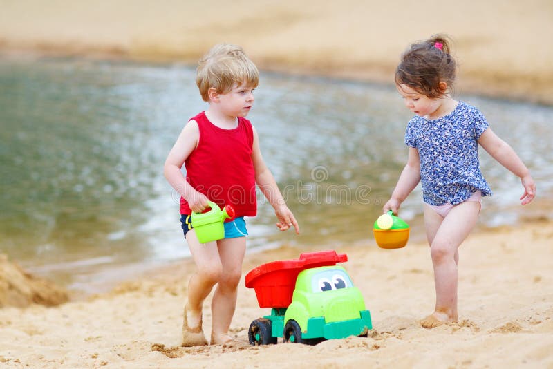 Le petit garçon et la fille d'enfant en bas âge jouant ainsi que le sable joue photographie stock Le petit garçon et la fille d'enfant en bas âge jouant ainsi que le sable joue photographie stock