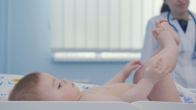 Le petit garçon mignon s'étend sur la couche et touche ses jambes