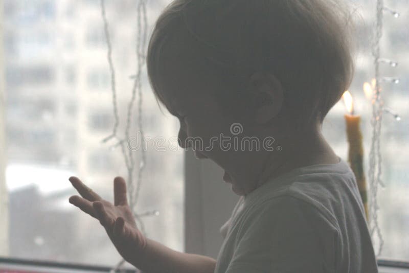 Le petit garçon vilain a touché le feu de bougie images stock Le petit garçon vilain a touché le feu de bougie images stock
