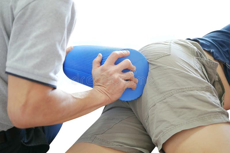 Le physiothérapeute traite le physio- massage des fonds patients par le rouleau bleu de mousse pour diminuer la douleur et pour a image libre de droits Le physiothérapeute traite le physio- massage des fonds patients par le rouleau bleu de mousse pour diminuer la douleur et pour a image libre de droits