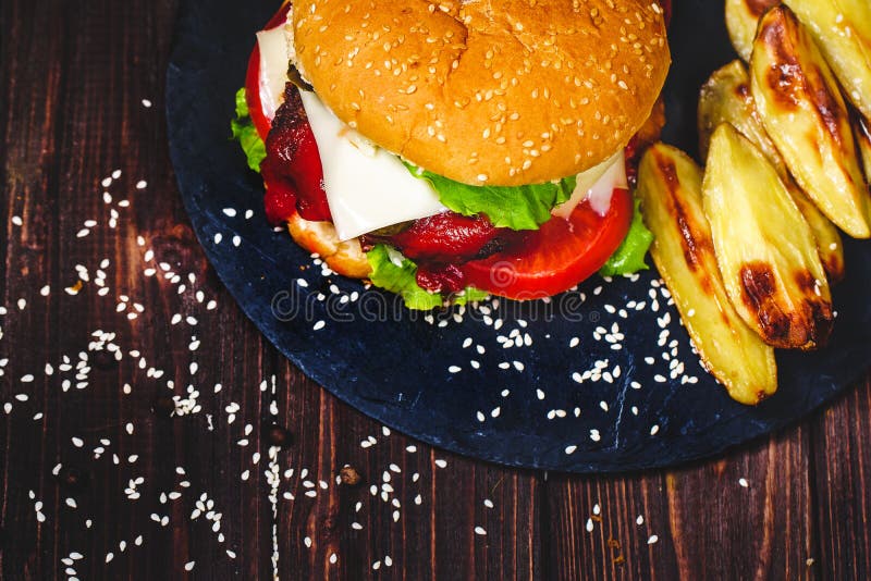 Le plan rapproch? de l'hamburger fait ? la maison de boeuf avec de la laitue et la pomme de terre a servi sur la planche ? d?coup photographie stock Le plan rapproch? de l'hamburger fait ? la maison de boeuf avec de la laitue et la pomme de terre a servi sur la planche ? d?coup photographie stock