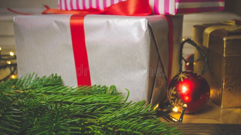 Le plan rapproché a modifié la tonalité l'image du grand boîte-cadeau avec le ruban rouge sur la table en bois à côté des décorat photos stock Le plan rapproché a modifié la tonalité l'image du grand boîte-cadeau avec le ruban rouge sur la table en bois à côté des décorat photos stock