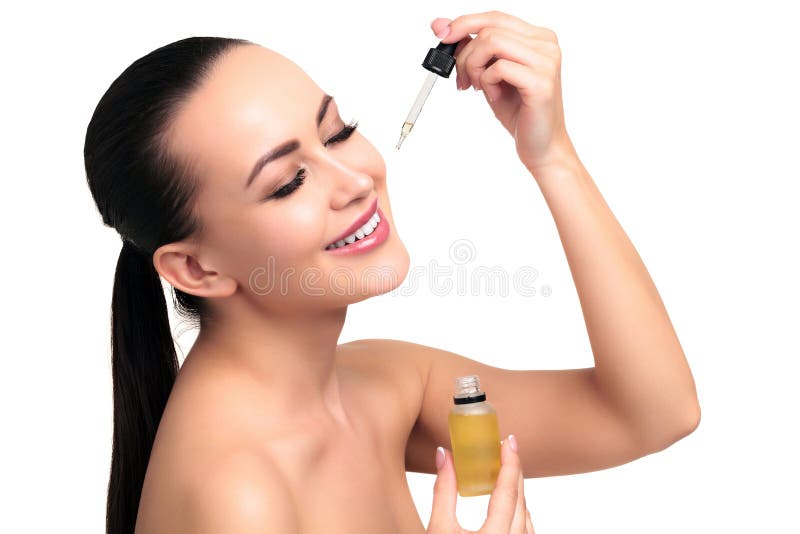 Le plan rapproché a tiré d'huile cosmétique s'appliquant sur le visage du ` s de jeune femme images libres de droits Le plan rapproché a tiré d'huile cosmétique s'appliquant sur le visage du ` s de jeune femme images libres de droits