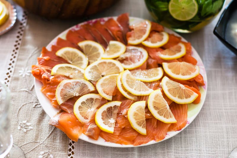 Le plat avec les saumons fumés découpés en tranches pêchent avec le citron photo libre de droits Le plat avec les saumons fumés découpés en tranches pêchent avec le citron photo libre de droits