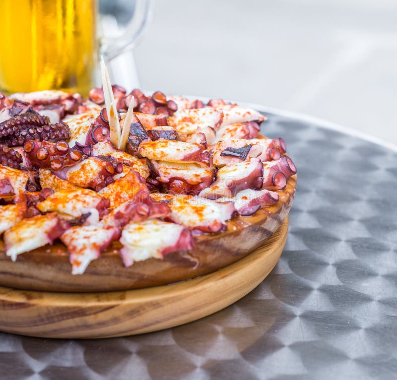 Le plat en bois délicieux du style galicien a fait cuire le poulpe et le verre de bière froide Pulpo une La gallega photographie stock libre de droits Le plat en bois délicieux du style galicien a fait cuire le poulpe et le verre de bière froide Pulpo une La gallega photographie stock libre de droits