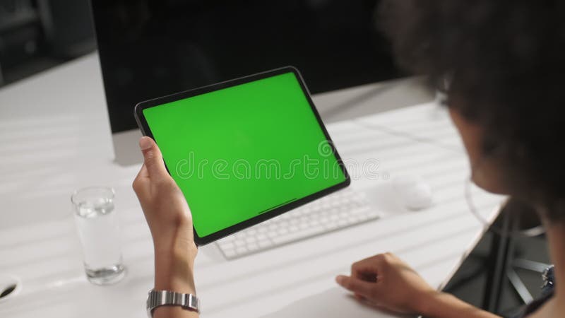 Le point de vue de l'épaulement de la femme à l'aide des gestes frappent à toute volée sur la tablette numérique d'écran vert prot clips vidéos