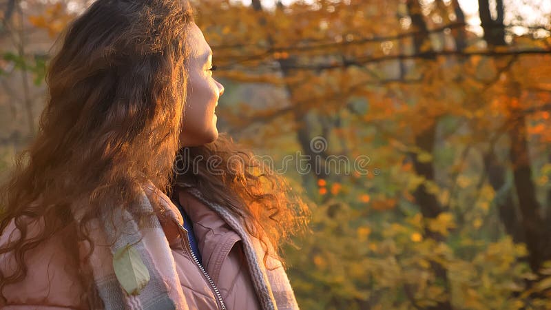 Le portrait arrière de la belle fille caucasienne aux cheveux bouclés a tourné son dos sur la caméra en parc automnal photo stock Le portrait arrière de la belle fille caucasienne aux cheveux bouclés a tourné son dos sur la caméra en parc automnal photo stock
